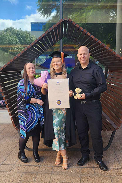 Nikia with her UniSA Alumni parents at her graduation ceremony