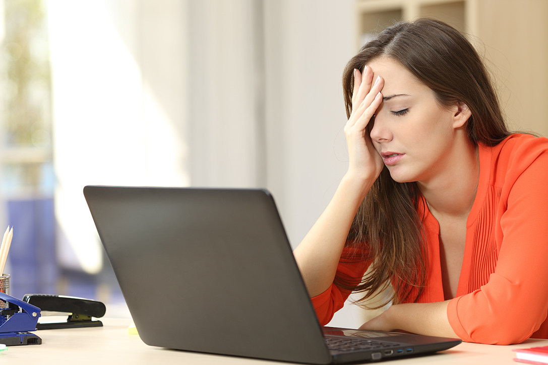 Woman at her computer with hand on her forehead