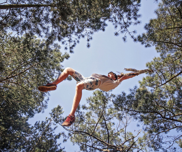 Boy swinging on a rope through tree canopy
