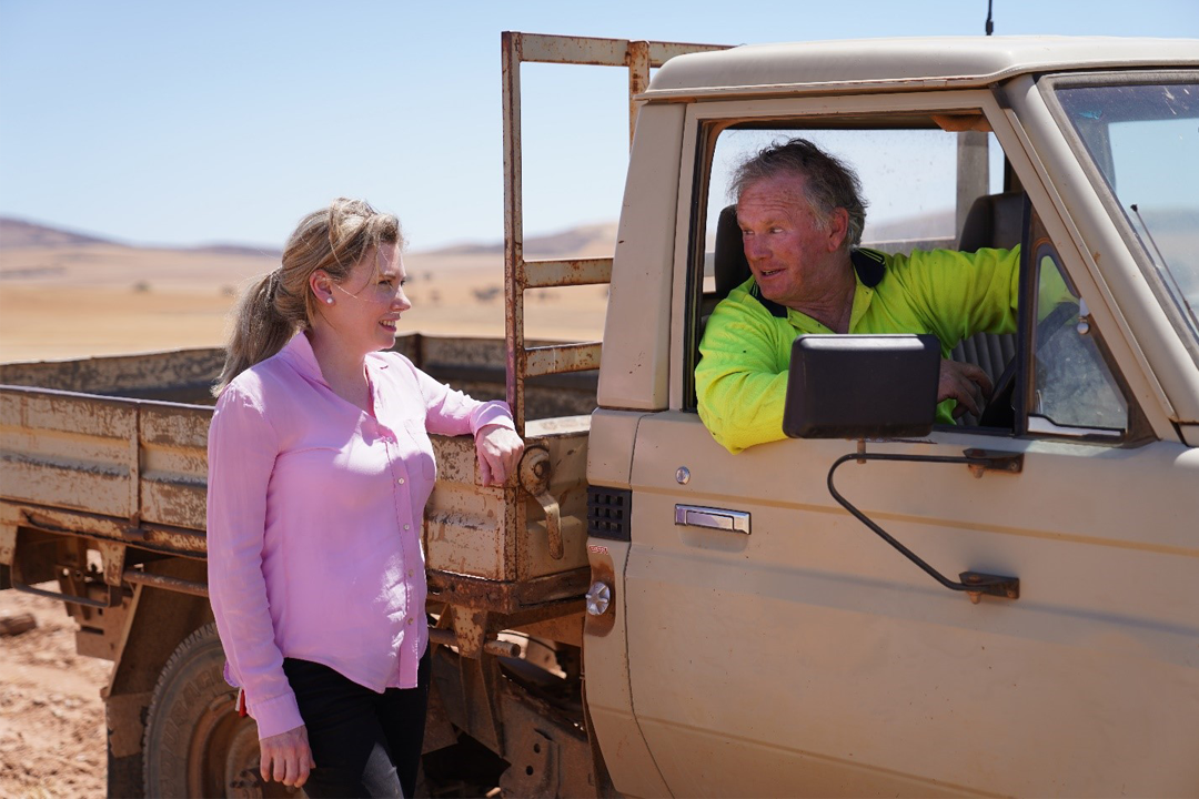 Dr Kate Gunn talking with a farmer in a ute in the field